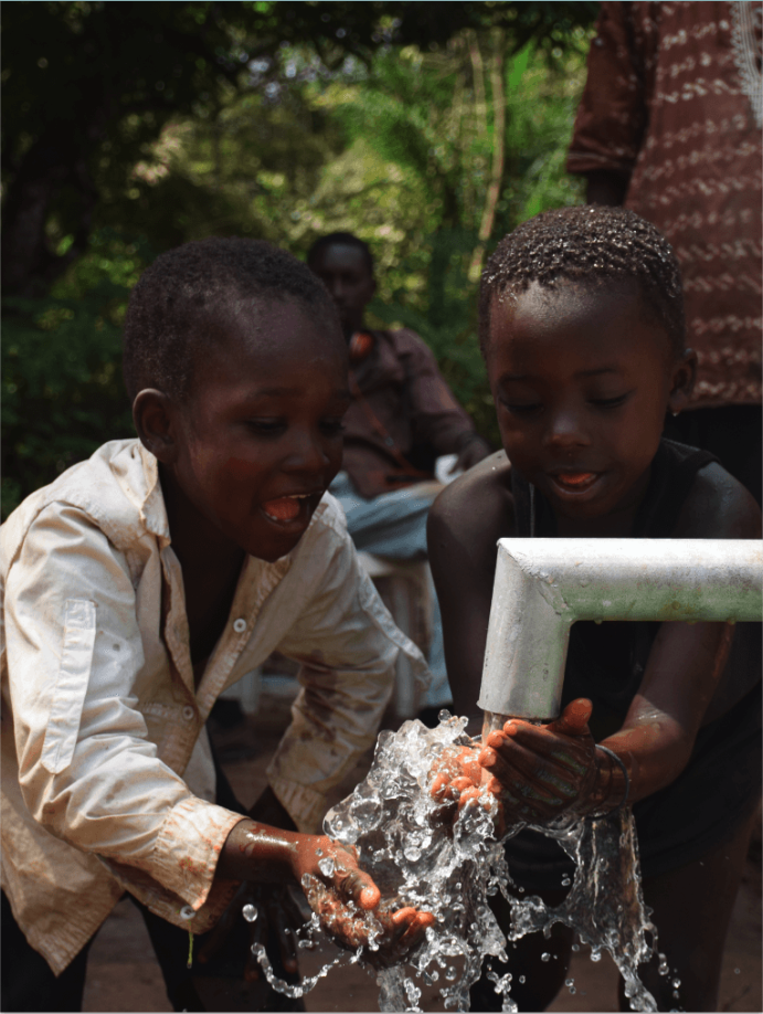 Two young children getting water from well